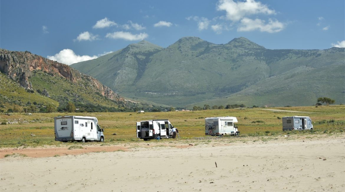 a group of four travel trailers parked in a field