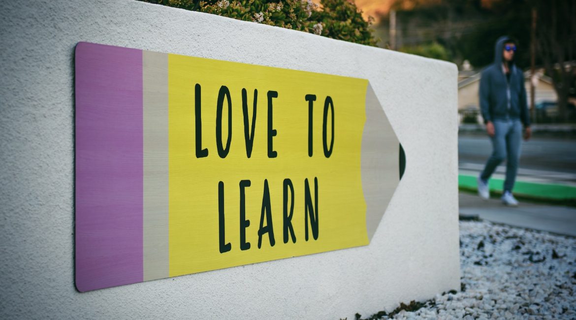 love to learn pencil signage on wall near walking man