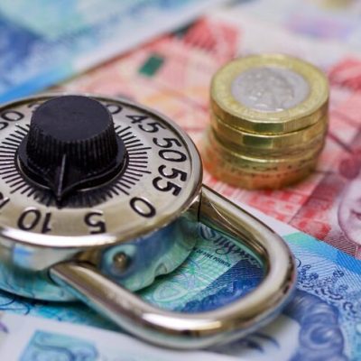 Combination lock and British currency symbolize security in finance.